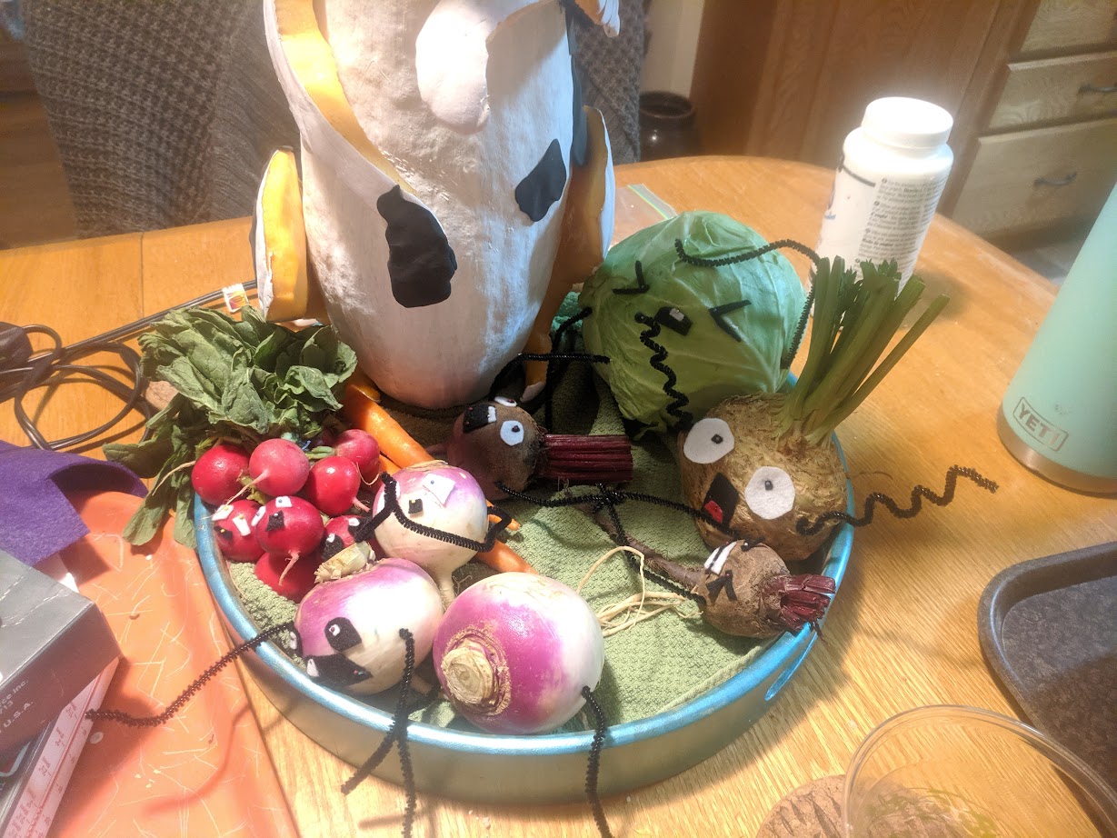 raddishes, turnips, beets and a cabbage adorned with felt faces and squiggly pipe cleaner arms appear to be screaming in terror.