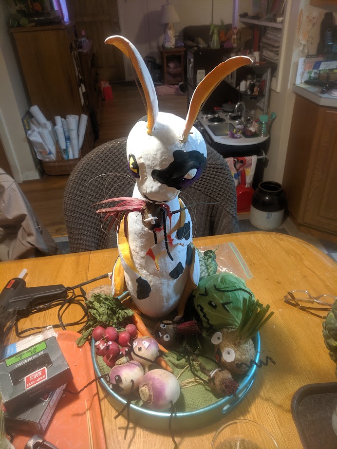 two pumpkins carved and painted to look like a sinister rabbit devouring screaming vegetables